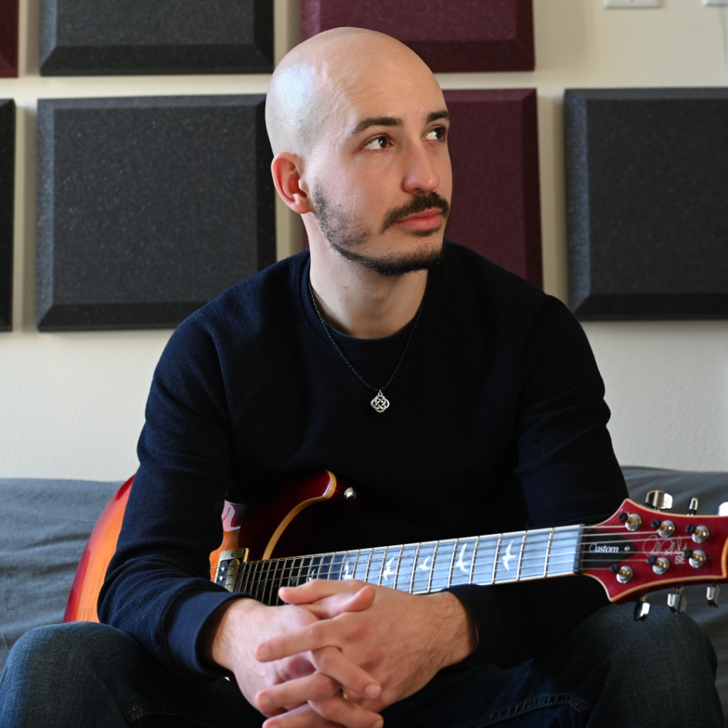 Jules sitting with a guitar on his lap
